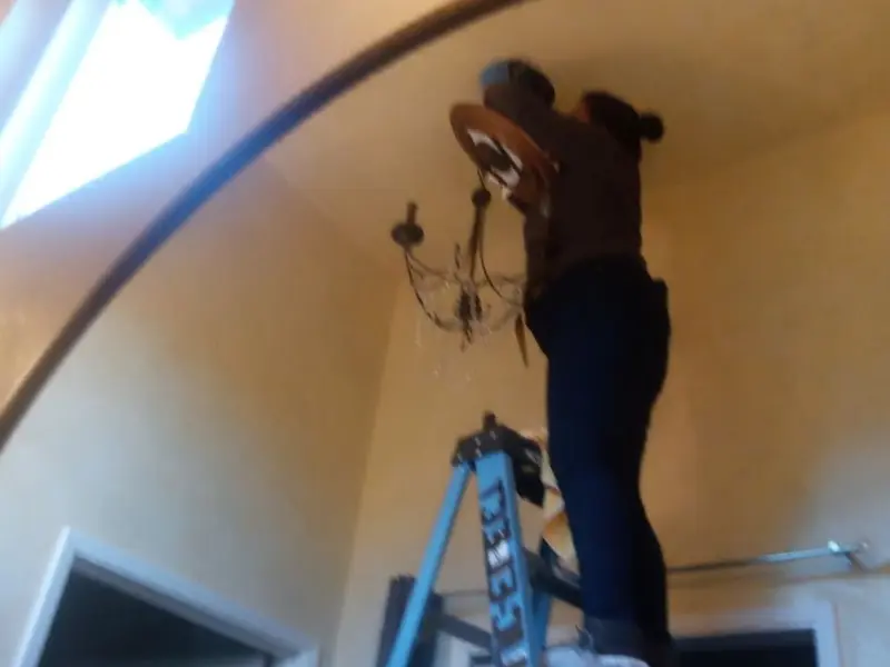 Electrician installing a chandelier in a Bon Secour residence